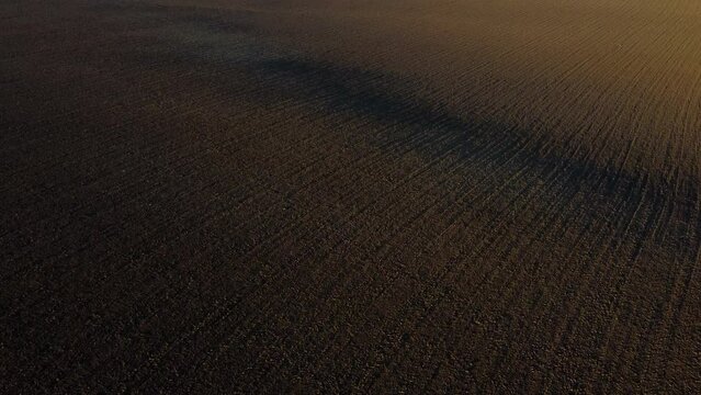 Landscape of plowed up land on an agricultural field on a sunny autumn day. Flying over the plowed earth with black soil. Agrarian background. Black soil. Ground earth dirt priming aerial drone view.