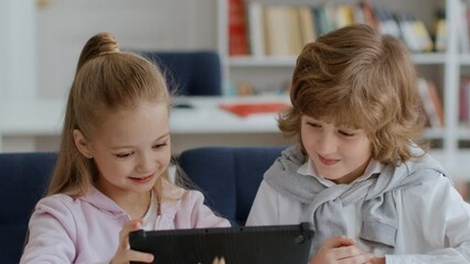 Children and friendship. Cute little boy and girl web surfing on digital tablet, playing together on break at school