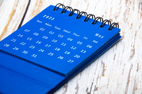 May 2023 blue table calendar on wooden cover background. Calendar concept