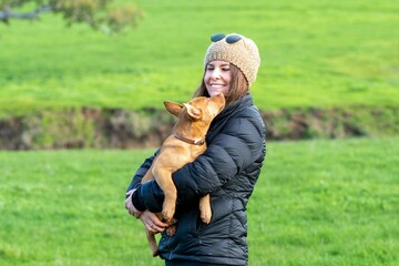 Naklejka na ściany i meble girl on a farm holding a puppy dog in her arms, tan kelpie puppy