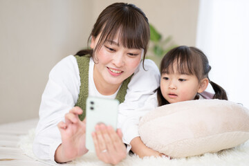 スマホで一緒に仲良く何かを探す親子　左にコピースペースあり