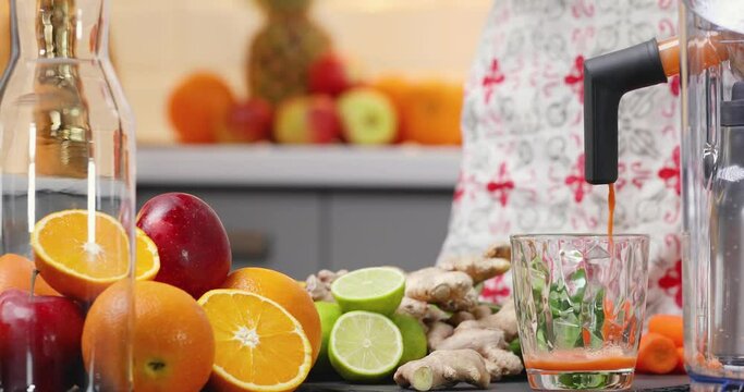 Squeezing carrot juice with juicer healthy citrus fruits in background. Intake vitamins detox, healthy diet and living concept