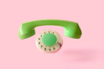 The handset and disc of an old retro phone on a pink background with the absence of the device...
