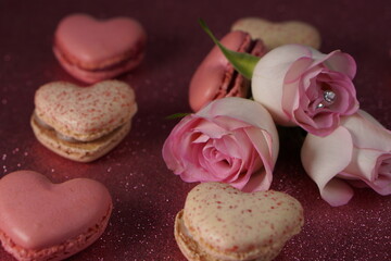 Heart-shaped macarons with roses on glittery pink background, Valentines day