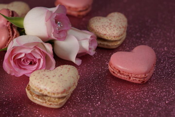Heart-shaped macarons with roses on glittery pink background, Valentines day