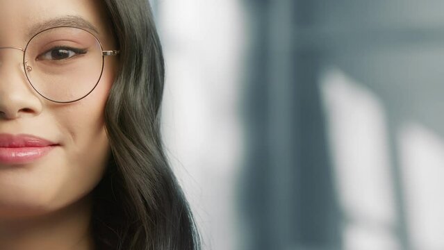 Close up portrait beautiful young asian multi-race business woman in modern glasses. Smiling young woman half face looking into camera with copy space on grey background. Career people, Female Beauty