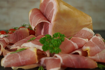 Traditional Italian smoked dry ham close-up composition with basil and tomato