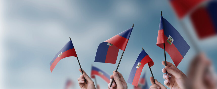 A group of people holding small flags of the Haiti in their hands