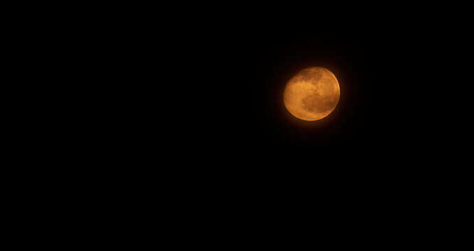 Orange full moon. High-resolution picture of the moon by telescope, with the moon illuminated at 90%