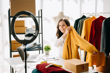 Fashion blogger concept, Young Asian women selling clothes on video streaming.Startup small business SME, using smartphone or tablet taking receive and checking