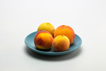 Fruits of ripe peaches on a dessert plate on a light background, close-up.