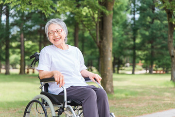 公園で車椅子に乗る高齢者女性(散歩・外出)
