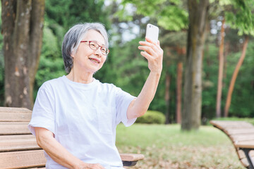 公園でスマホを使う高齢者女性（アプリ・操作・検索）
