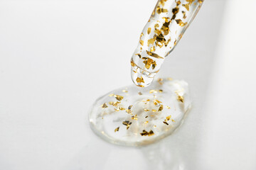 Pipette with Serum drop with gold particles close-up, copy space. Beauty skin care product swatch.
