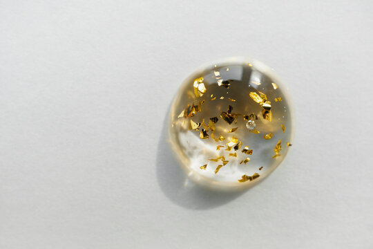 Serum drop with gold particles close-up, copy space. Beauty skin care product swatch. - Powered by Adobe