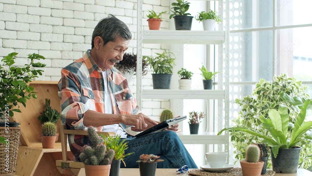 Wall mural cheerful elderly asian man relaxing holding and using digital tablet chatting with family by social 