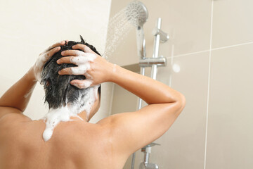 A man is washing his hair with shampoo