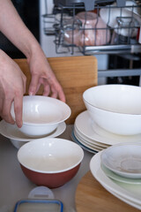 Women's hands sort clean dishes from the dishwasher