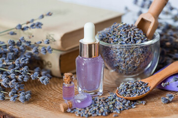 Fototapeta na wymiar Aromatherapy. Massage and spa. Cosmetic bottles of lavender essential oil, old books, dried flowers and lavender seeds on a wooden stand. Natural cosmetics for the body.