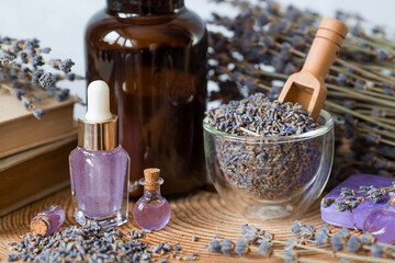 Aromatherapy. Massage and spa. Cosmetic bottles of lavender essential oil, old books, dried flowers and lavender seeds on a wooden stand. Natural cosmetics for the body.
