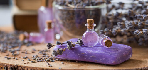 Obraz na płótnie Canvas Aromatherapy. Massage and spa. Cosmetic bottles of lavender essential oil, dried flowers and lavender seeds on a wooden stand. Natural cosmetics for the body.