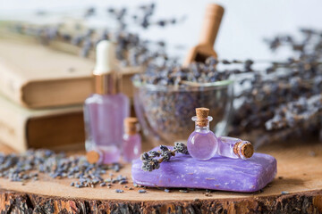 Aromatherapy. Massage and spa. Cosmetic bottles of lavender essential oil, old books, dried flowers and lavender seeds on a wooden stand. Natural cosmetics for the body.