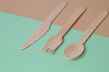 Eco-friendly disposable kitchen utensils on a beige-green background. Wooden forks, spoons and knives. Ecology, the concept of zero waste.