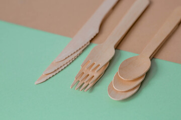 Eco-friendly disposable kitchen utensils on a beige-green background. Wooden forks, spoons and...