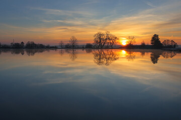 Obraz premium Calm reflection sunrise on pond in winter. Czech tranquil landscape background