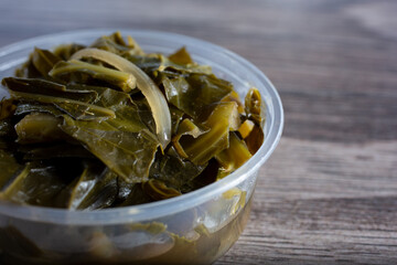 A closeup view of a plastic container of collard greens.