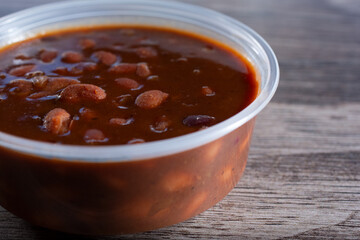 A closeup view of a plastic container of baked beans.