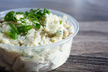 A top down view of a plastic container of potato salad.