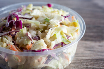 A closeup view of a plastic container of coleslaw.