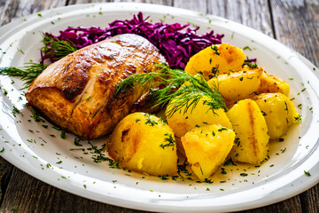 Fried pork loin with boiled potatoes and red cabbage on wooden table
