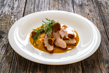 Fried veal loin in chanterelle mushrooms sauce on wooden table
