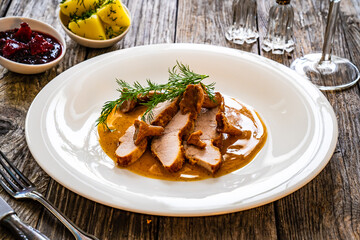 Fried veal loin in chanterelle mushrooms sauce on wooden table

