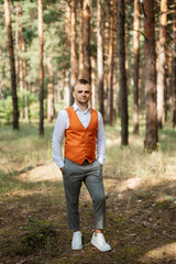 portrait of the groom in a gray suit and an orange vest