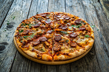 Circle pizza chorizo  with chicken nuggets and mozzarella, on wooden table
