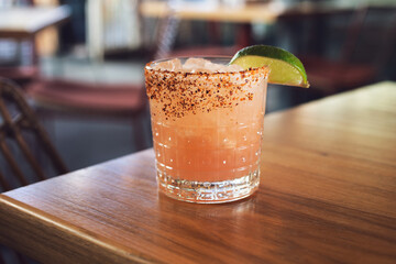 A view of a pink tequila cocktail on the table corner, in a restaurant setting.