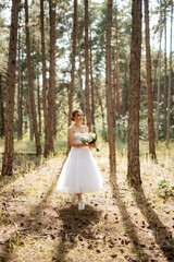 Obraz na płótnie Canvas young bride in a white short dress in a spring pine forest