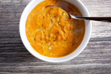 A top down view of a bowl of butter chicken.