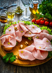 Big sandwich with mortadella with pistachios and lettuce on wooden table
