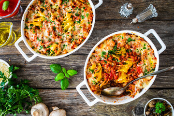 Noodle casserole with minced meat, mozzarella cheese and vegetables on wooden table
