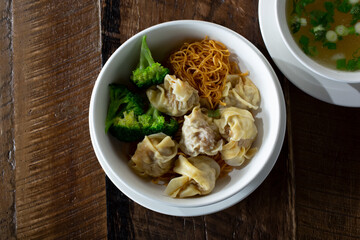 A top down view of a bowl of wonton noodle soup.