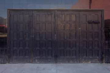 A view of several black doors, holding mush wear and tear.