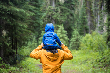 Rear view of Father carrying son on shoulders during a hike.