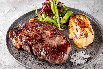Grilled Ribeye Steak on plate with Potato gratin and salad