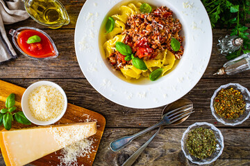 Fusilli with minced meat, tomato sauce, parmesan cheese and basil served on wooden table
