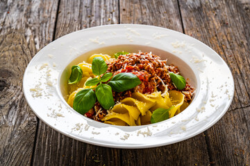Fusilli with minced meat, tomato sauce, parmesan cheese and basil served on wooden table
