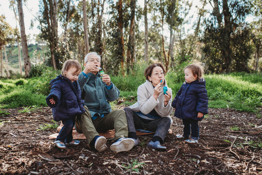 Grandparents blowing bubbles outside for granddaughters